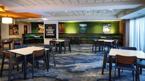 A hotel lobby with multiple seating areas, including tables and booths, and a large mural on the back wall.