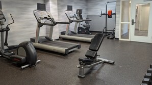 A gym with treadmills, an elliptical, and a bench press.