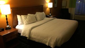 A hotel room with a large bed, two bedside lamps, a nightstand, and a telephone.