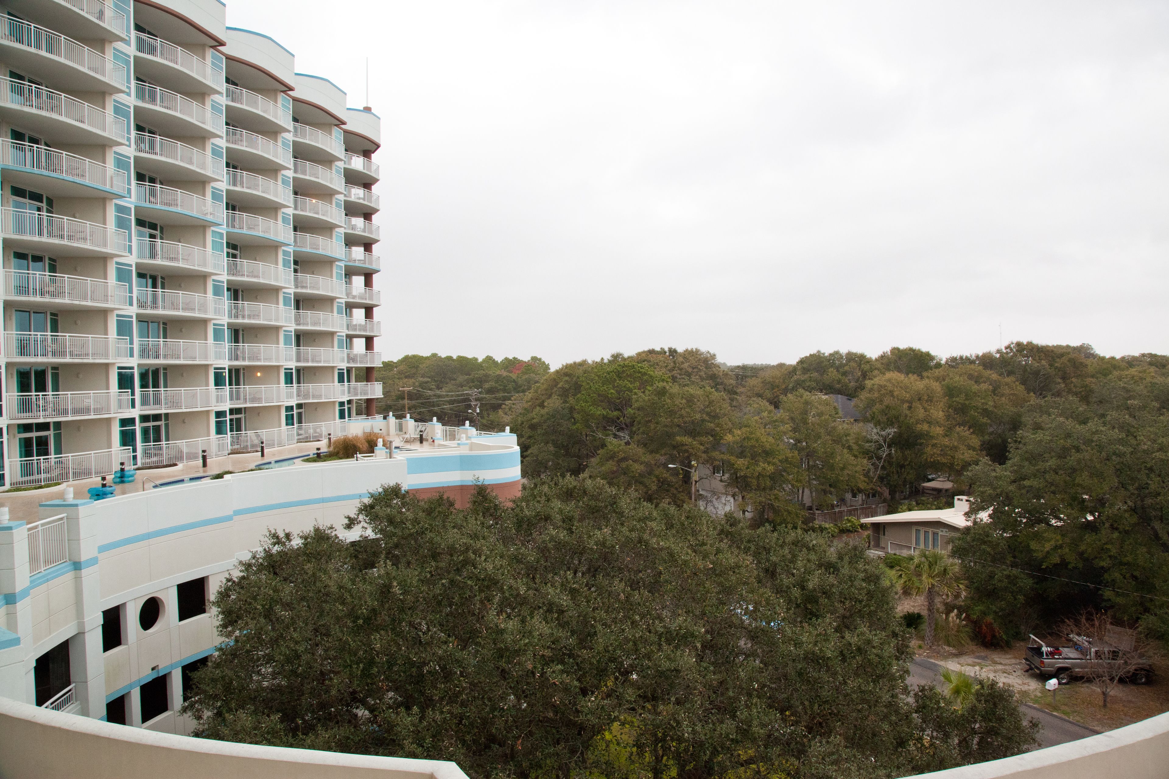 A multi-story hotel with balconies, surrounded by dense trees.