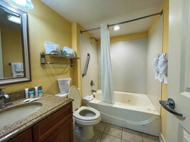 Un baño con lavamanos, inodoro, bañera y cortina de ducha.