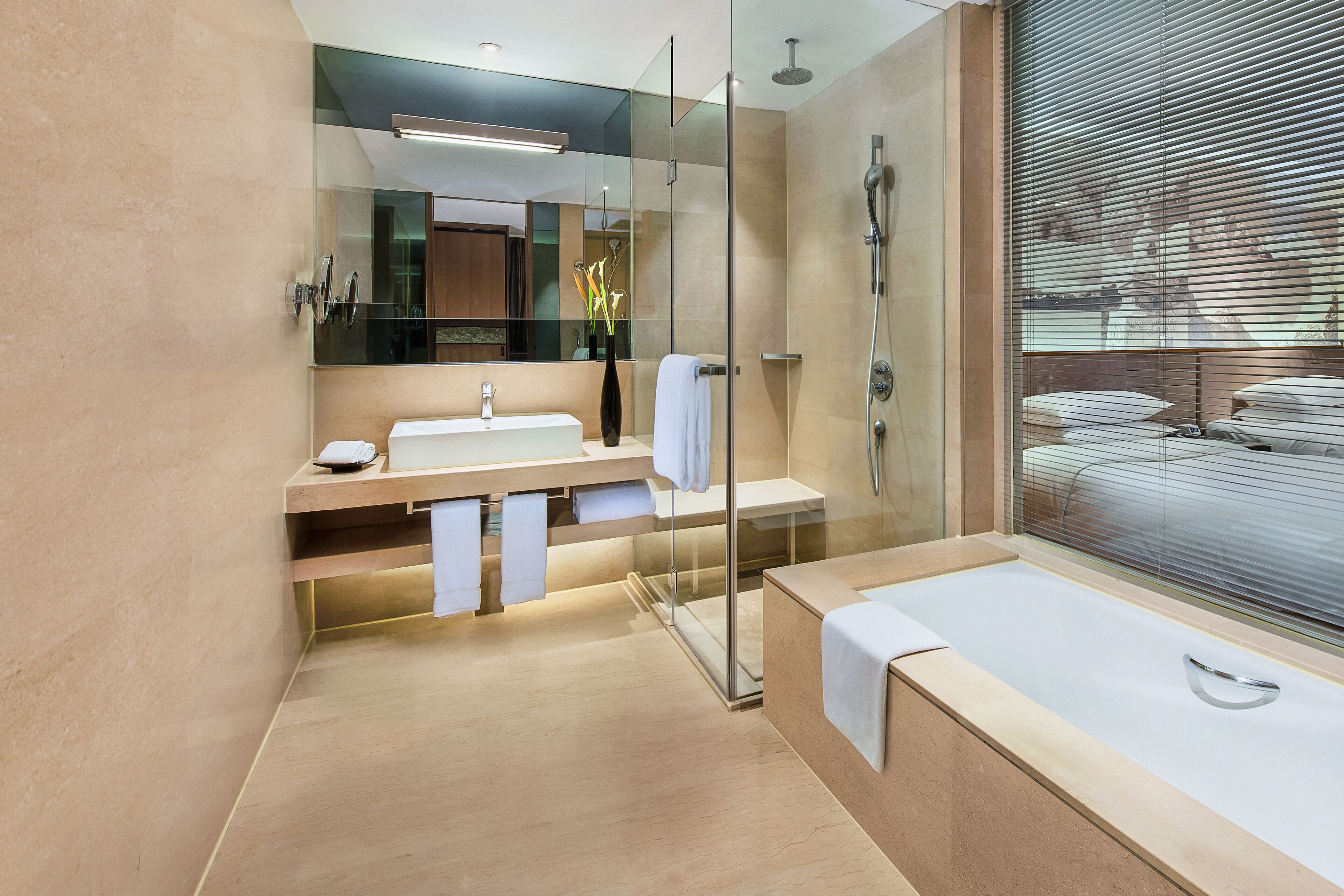 A modern bathroom with a glass-enclosed shower, a large mirror, a bathtub, and a vanity with a sink and towel rack.