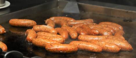 Sausages being grilled on a flat cooking surface.