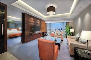 Une chambre d’hôtel équipée d’un lit, d’un coin salon, d’une télévision et offrant une vue sur le paysage urbain.