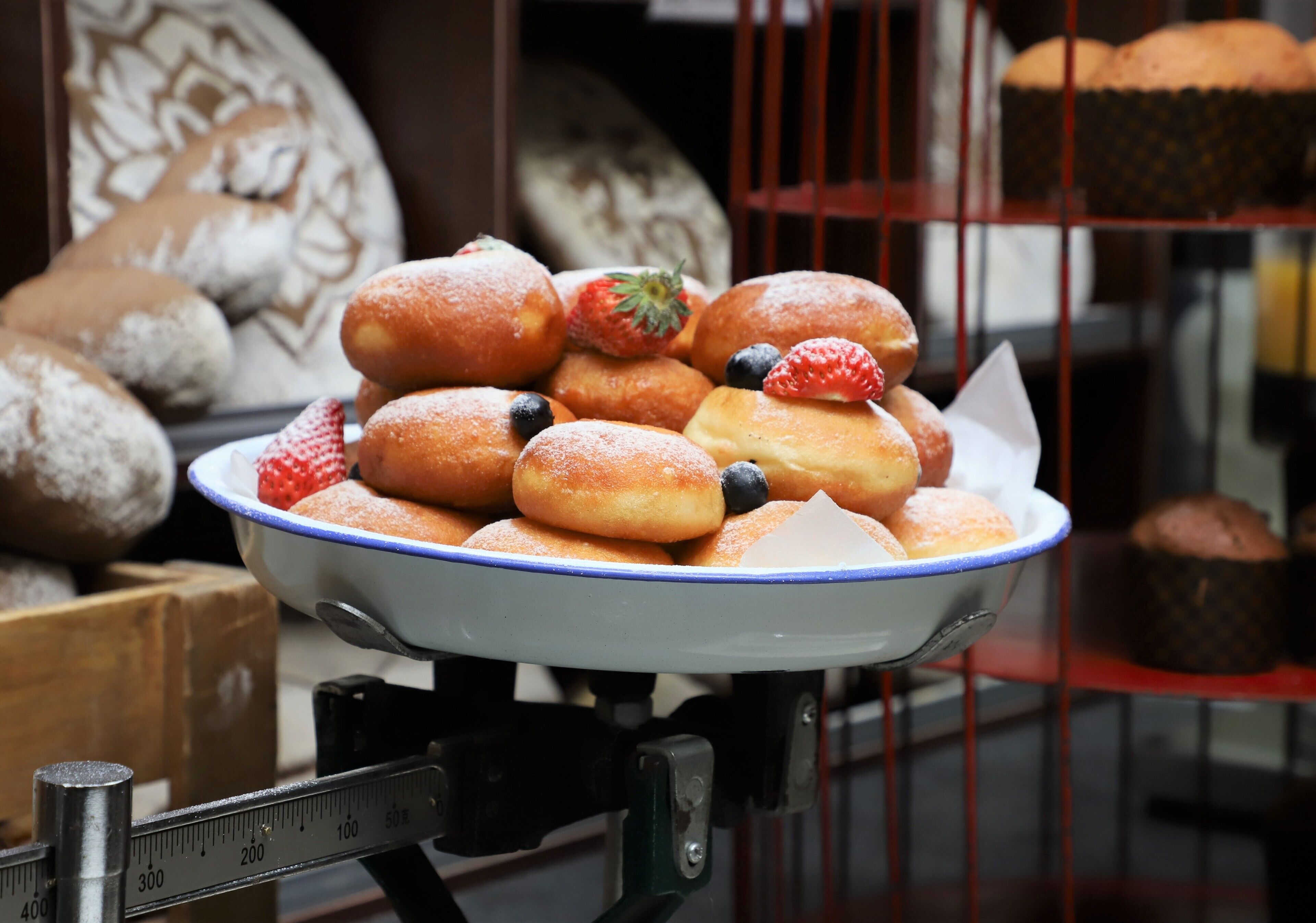 A display of assorted pastries, including donuts and muffins, arranged on a stand with a measuring scale.