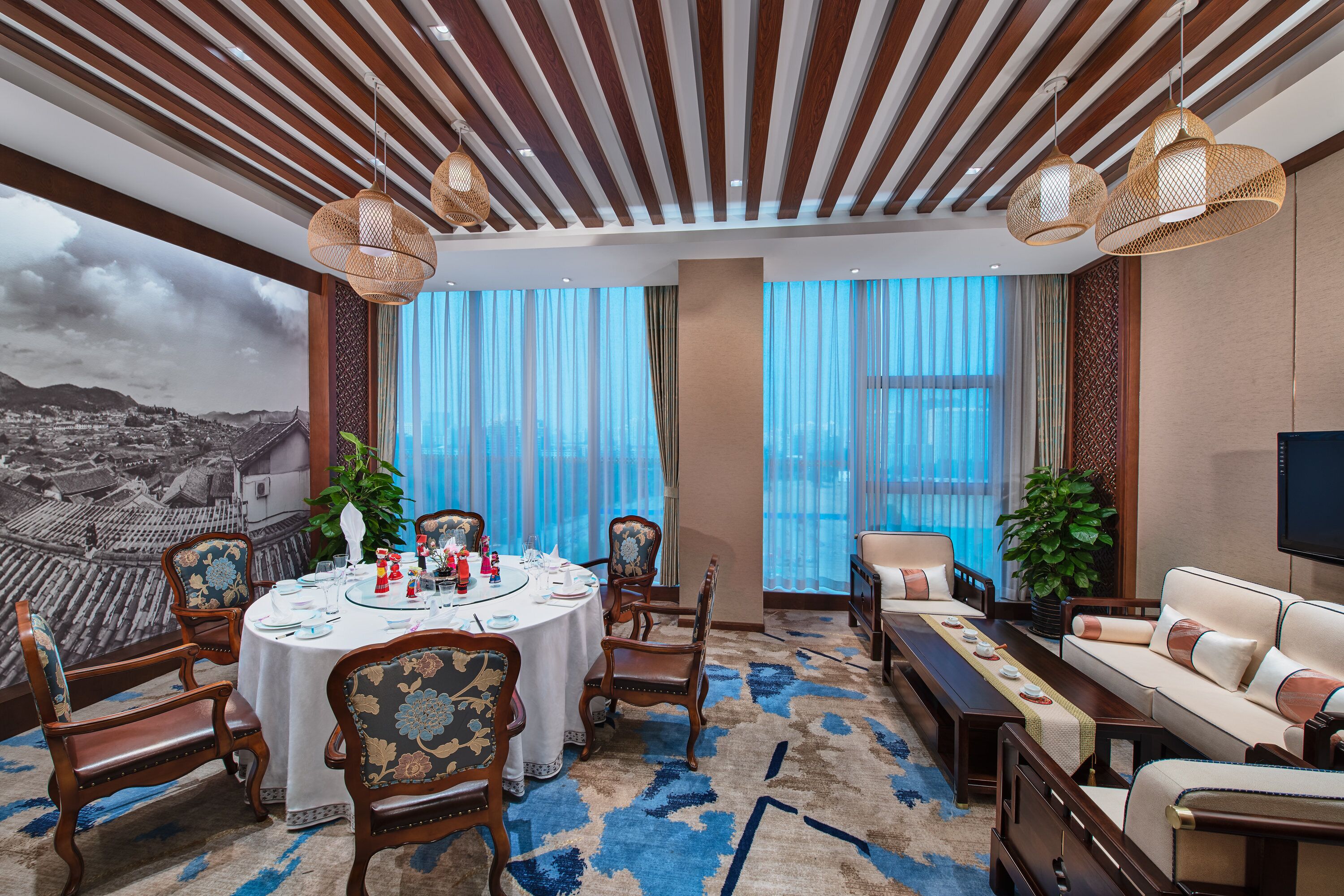 Habitación de hotel con comedor, un conjunto de sofás y un ventanal con vistas a la ciudad.