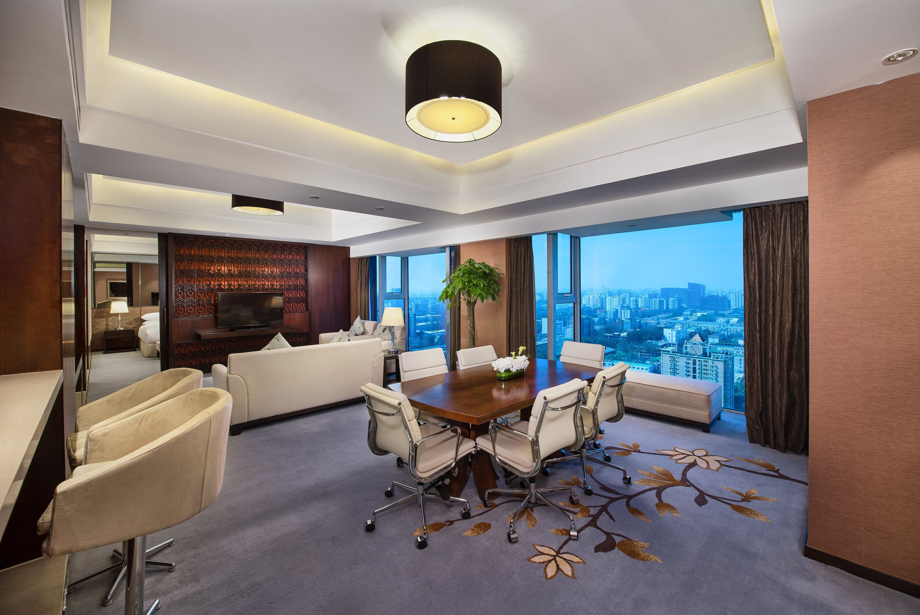 Une chambre d’hôtel moderne offrant une vue imprenable sur la ville, avec un coin repas comprenant une table et des chaises, un canapé et un téléviseur.