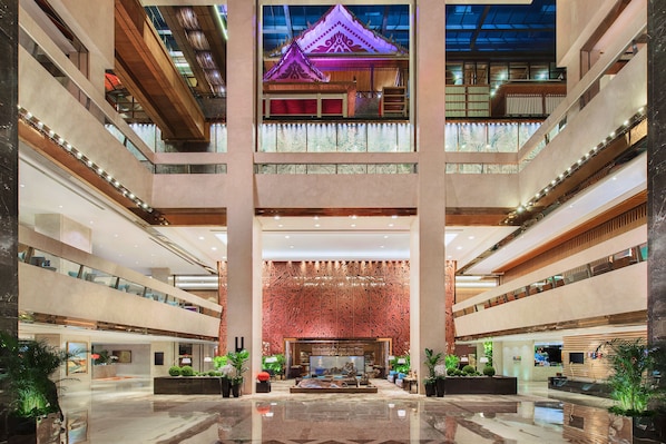 Un hall d’hôtel à plusieurs niveaux, doté d’un atrium central, de nombreux étages et d’un élément architectural traditionnel situé en hauteur.