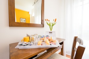 A breakfast tray with pastries, a yellow mug, and a vase with tulips on a wooden table in a hotel room. - B&B Antiche Armonie (Florence)