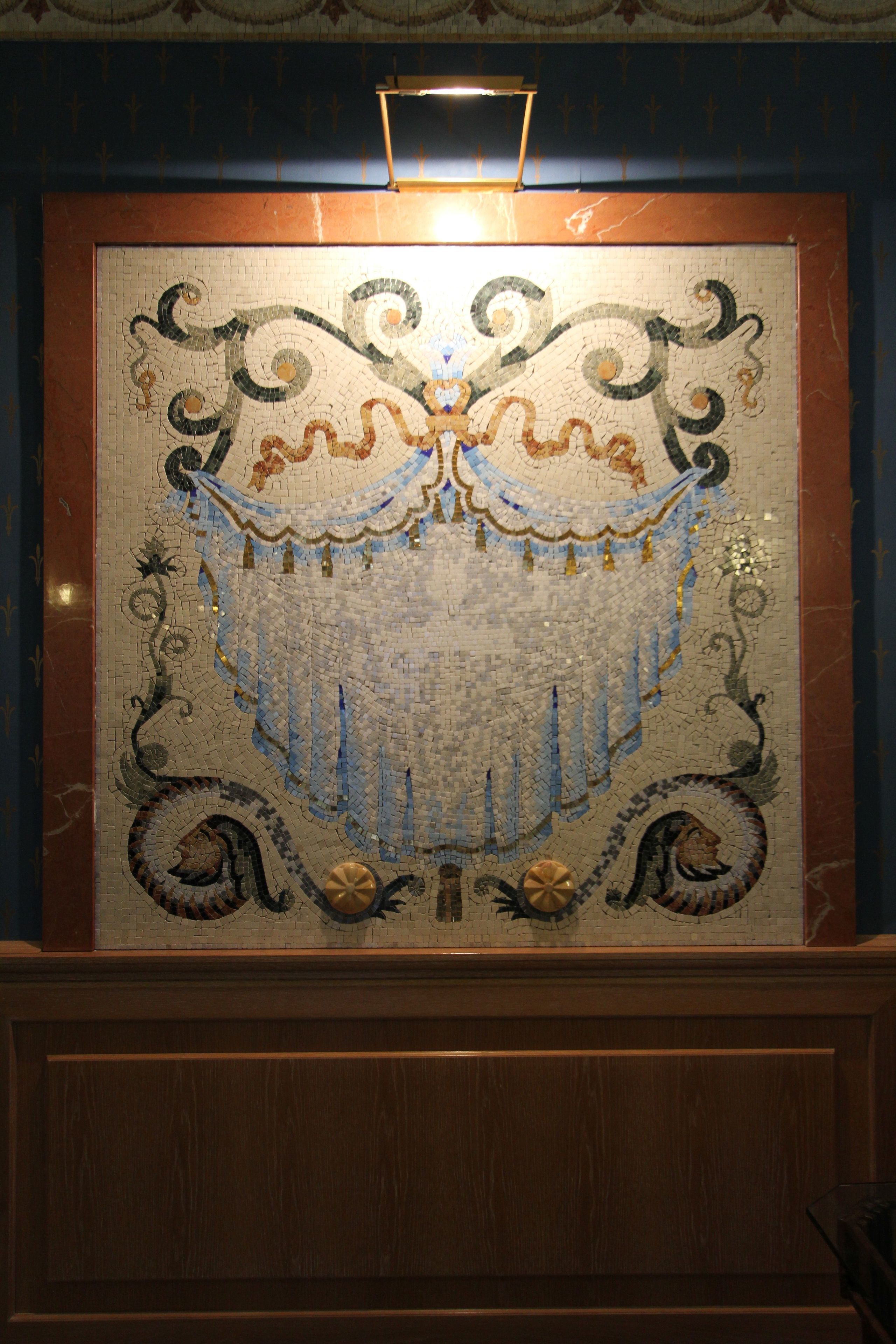 Eine Mosaikwand mit aufwendigen Mustern und einem hölzernen Rahmen.