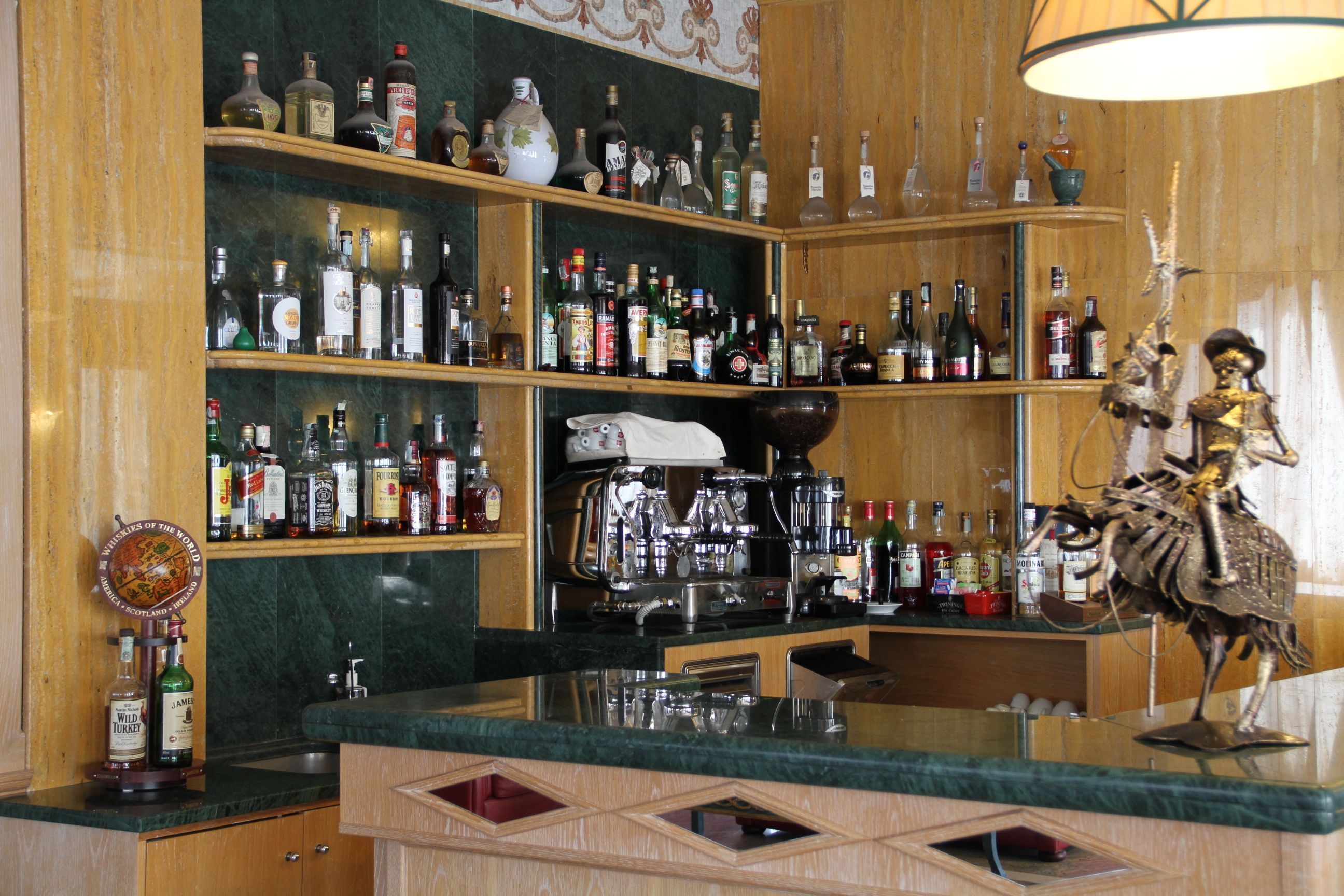 A bar area with shelves of liquor bottles, a coffee machine, and a decorative lobster statue.