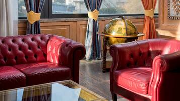 A room with a red leather sofa, a glass coffee table, and a globe on a wooden table.