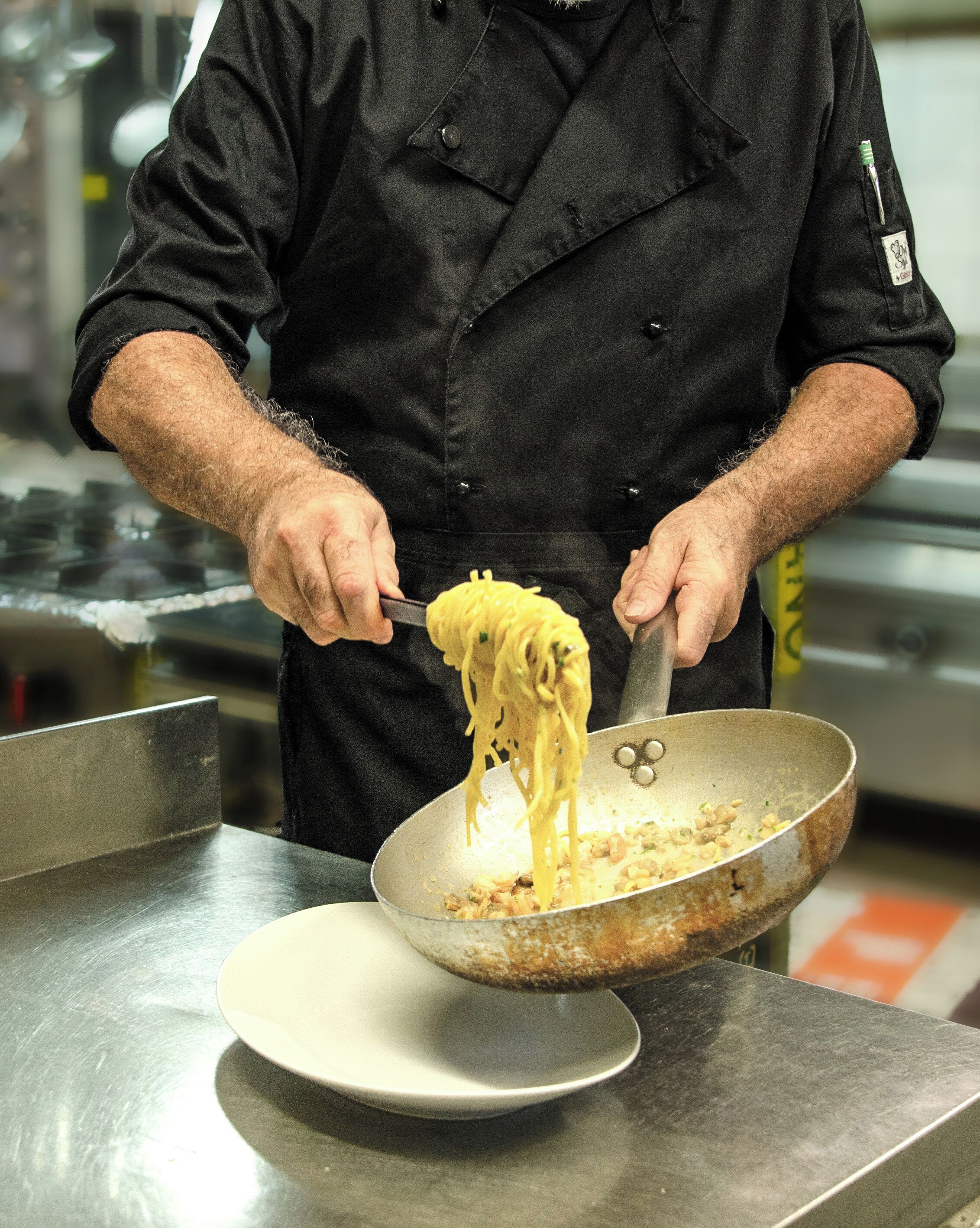 A person cooking spaghetti in a pan.