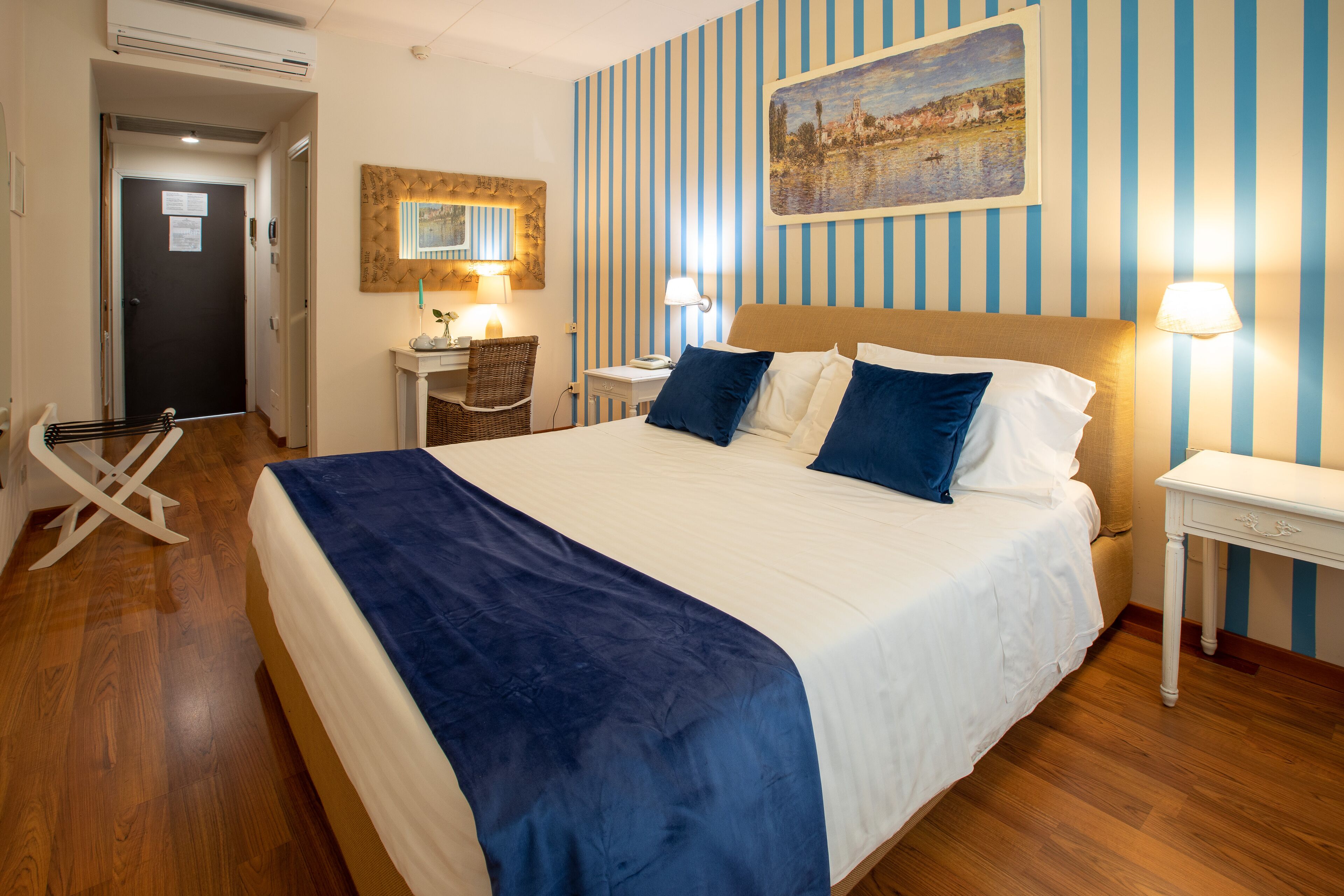 Ein Hotelzimmer mit einem großen Bett, einem Schreibtisch mit Stuhl, einem kleinen Tisch und einem Bild an der Wand.