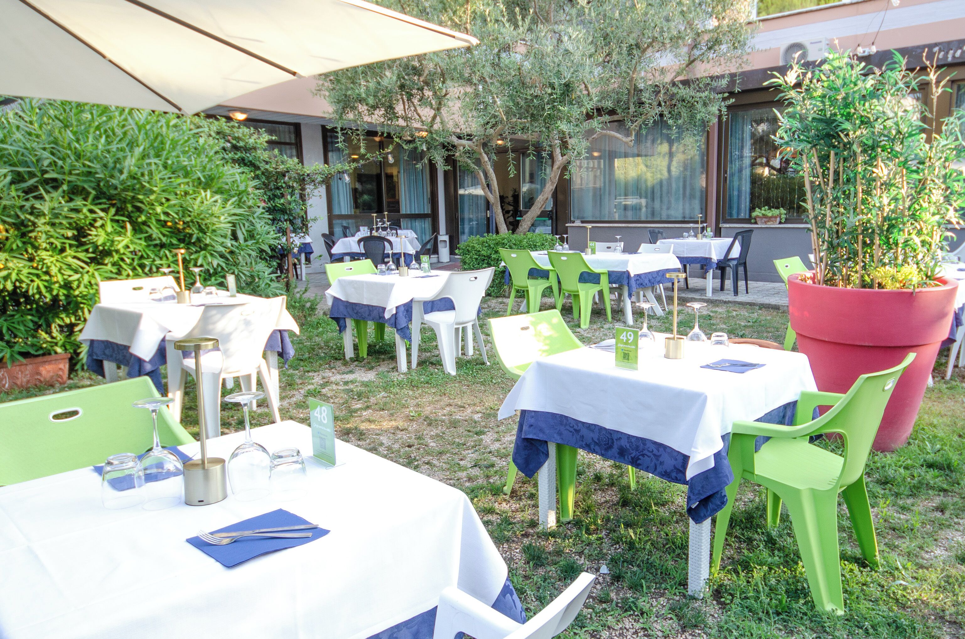 An outdoor dining area with tables and chairs, some with umbrellas.