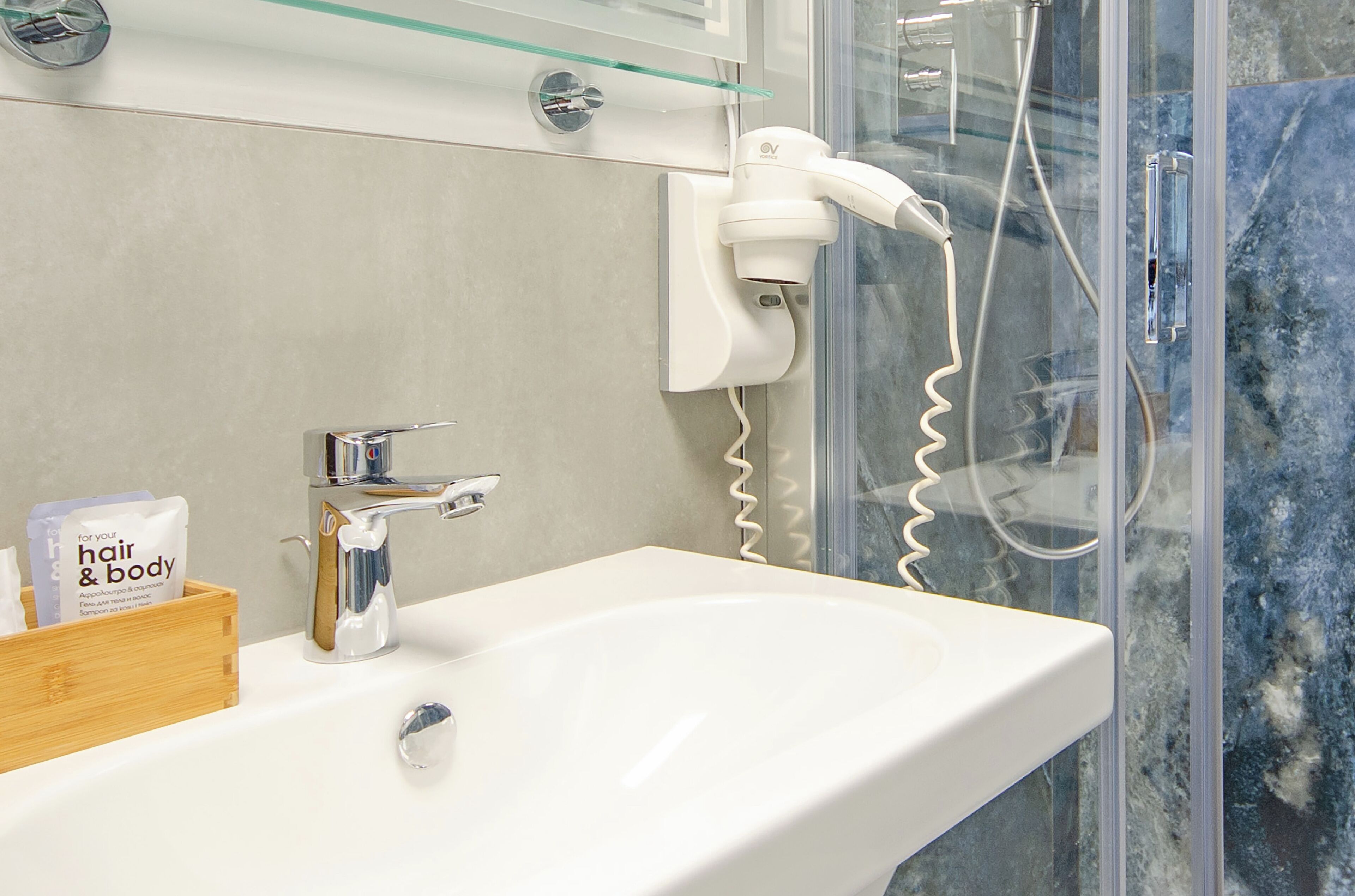 Casa de banho com uma sanita branca, um secador de cabelo e uma caixa de madeira com produtos de higiene pessoal.