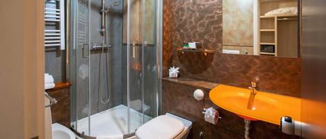Un baño moderno con ducha de vidrio, inodoro blanco y tocador con lavamanos naranja.