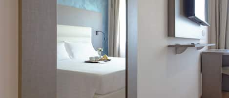 Una habitación de hotel moderna con cama, mesita de noche y un espejo sobre el lavabo.
