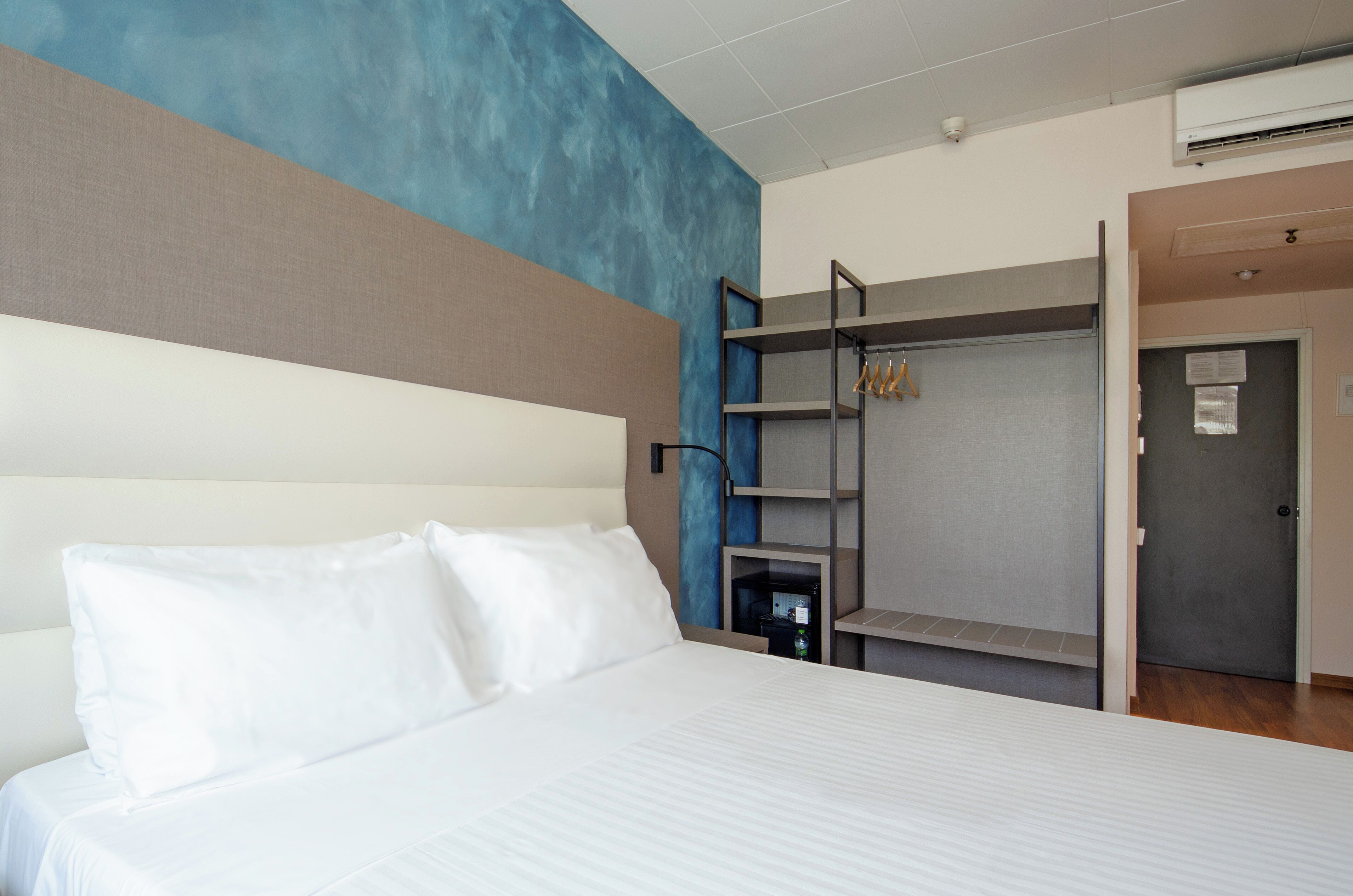 A hotel room with a bed, a wardrobe, and a door.
