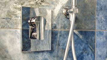A chrome showerhead and control panel mounted on a tiled wall.