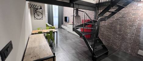 A modern interior with a staircase, a dining area, and a brick wall.