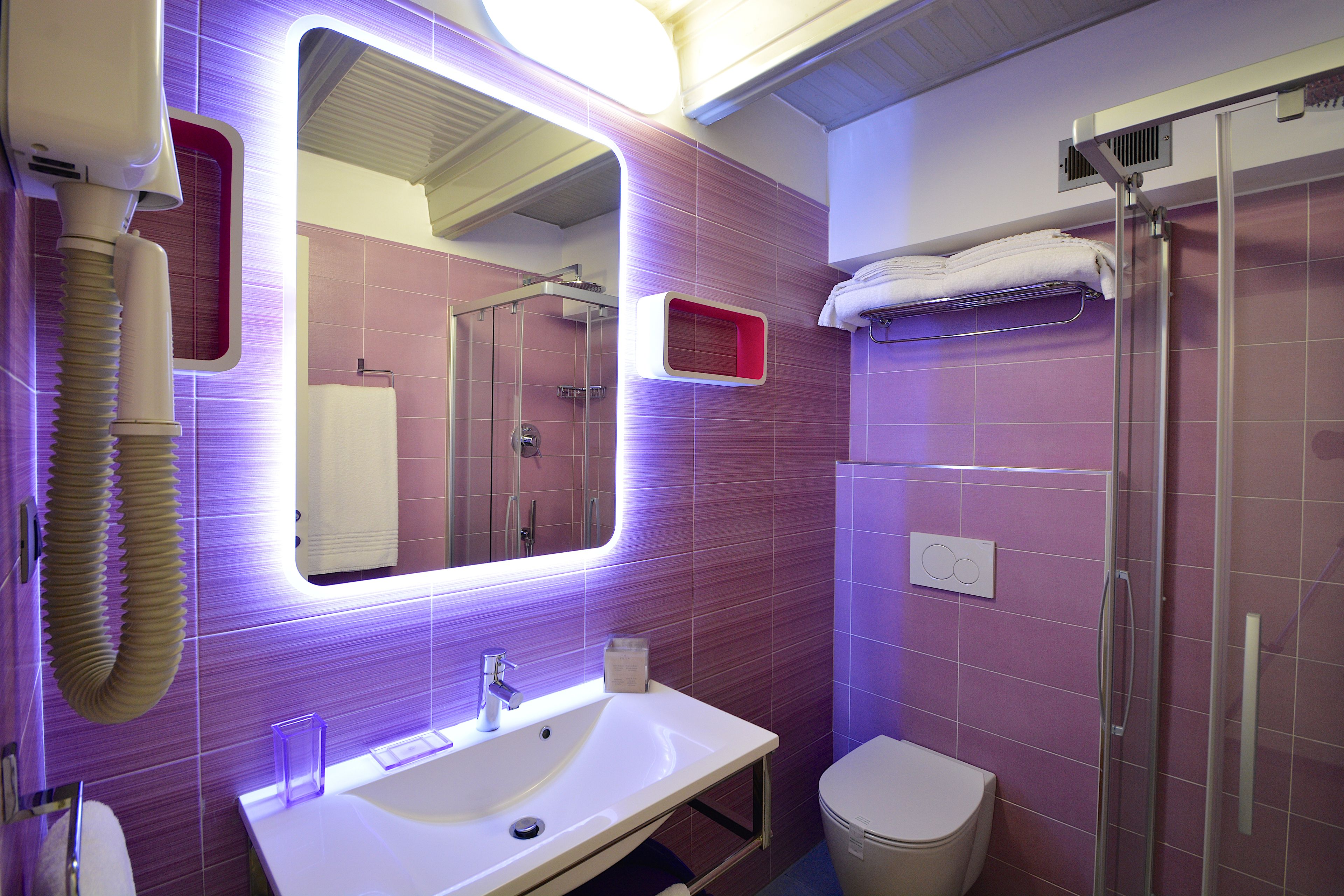 A modern bathroom with a large mirror, a sink, a toilet, and a shower.