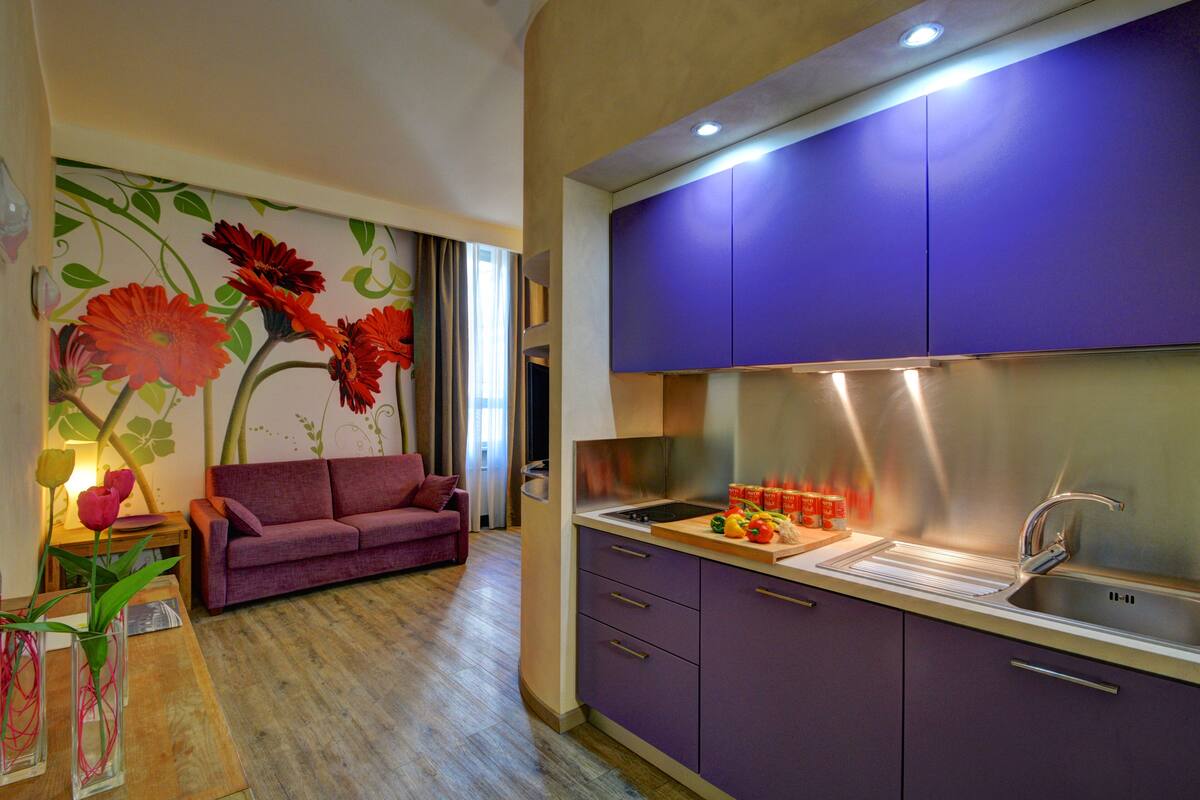 Une cuisine moderne avec des meubles de couleur violette et des appareils électroménagers en acier inoxydable.