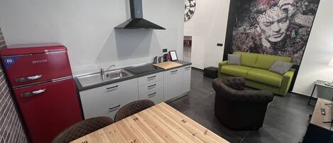 Una cocina moderna con un refrigerador rojo, una mesa de comedor de madera y un sofá verde.
