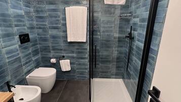 Une salle de bain moderne dotée d’une douche à parois de verre, de toilettes et d’un bidet.