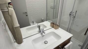 A modern bathroom with two sinks, a glass shower enclosure, and a mirror.