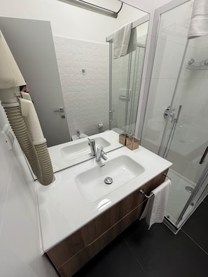 A modern bathroom with two sinks, a glass shower enclosure, and a mirror. - Residence Star (Turin)