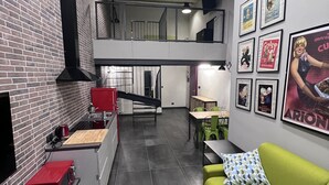 Una cocina moderna con pared de ladrillo, microondas rojo y sofá verde.