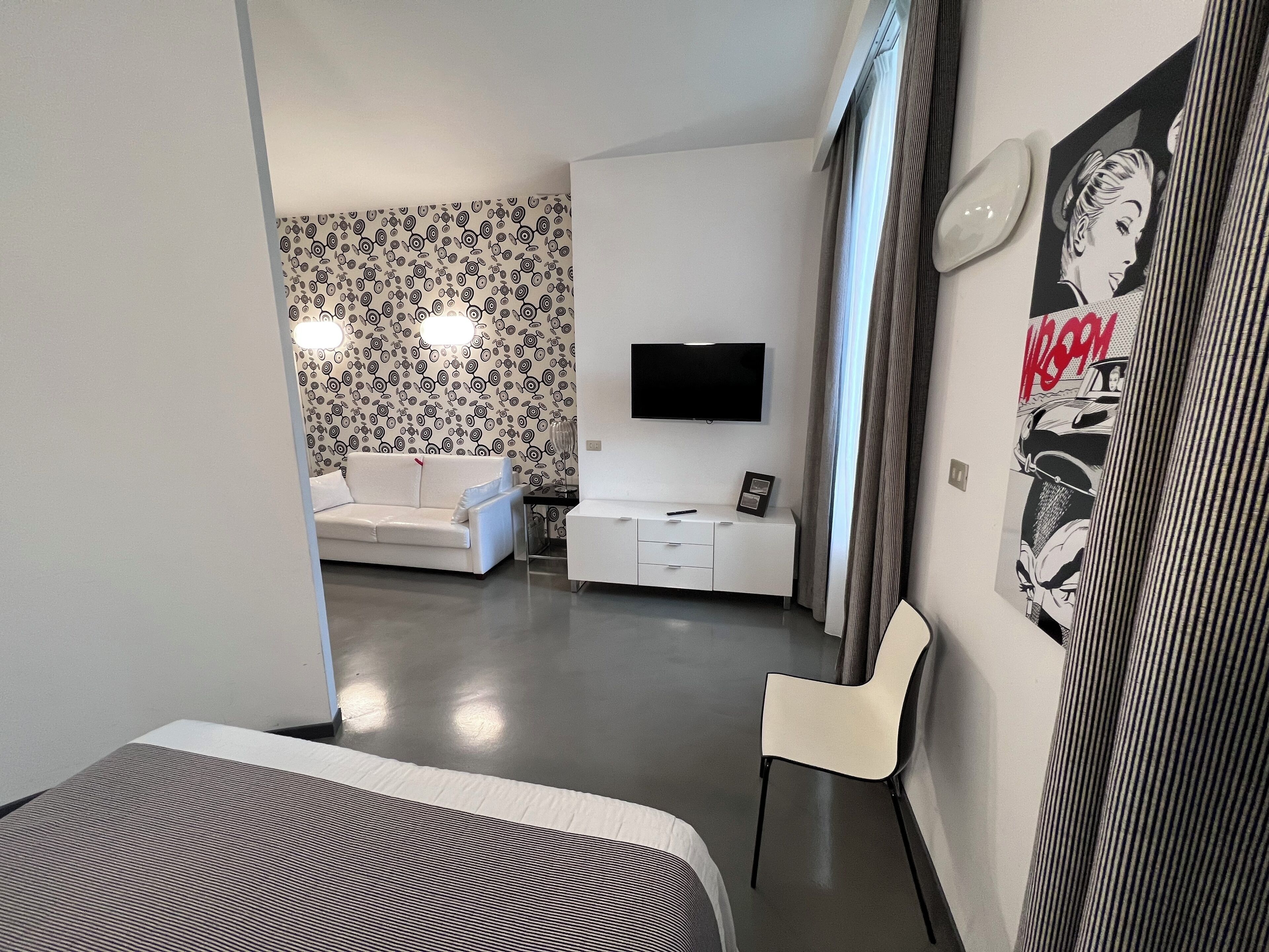 Un salon moderne avec un canapé blanc, un téléviseur à écran plat et un papier peint à motifs.