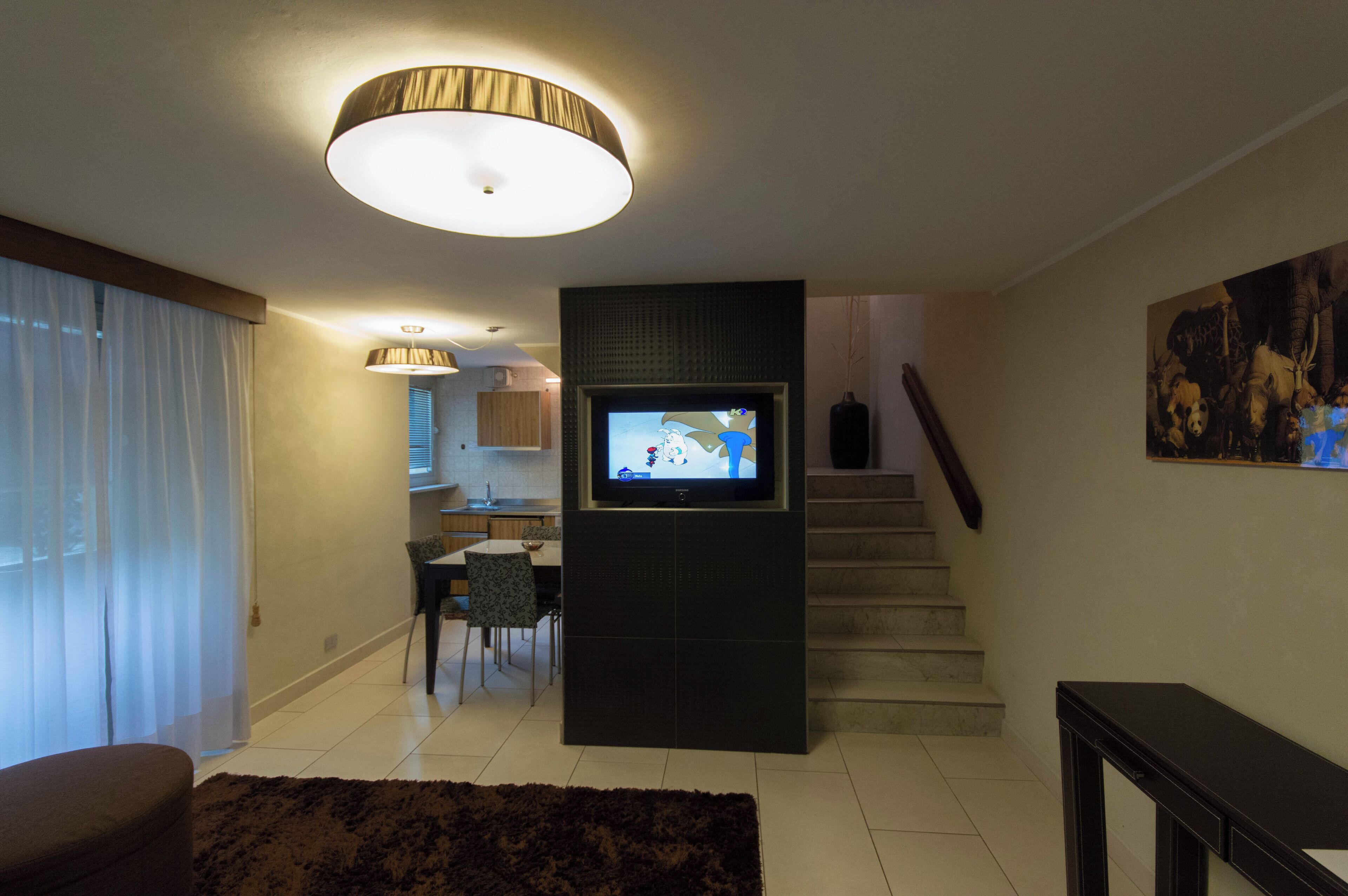 Un salon moderne doté d’un téléviseur à écran plat, d’un escalier et d’un coin repas.