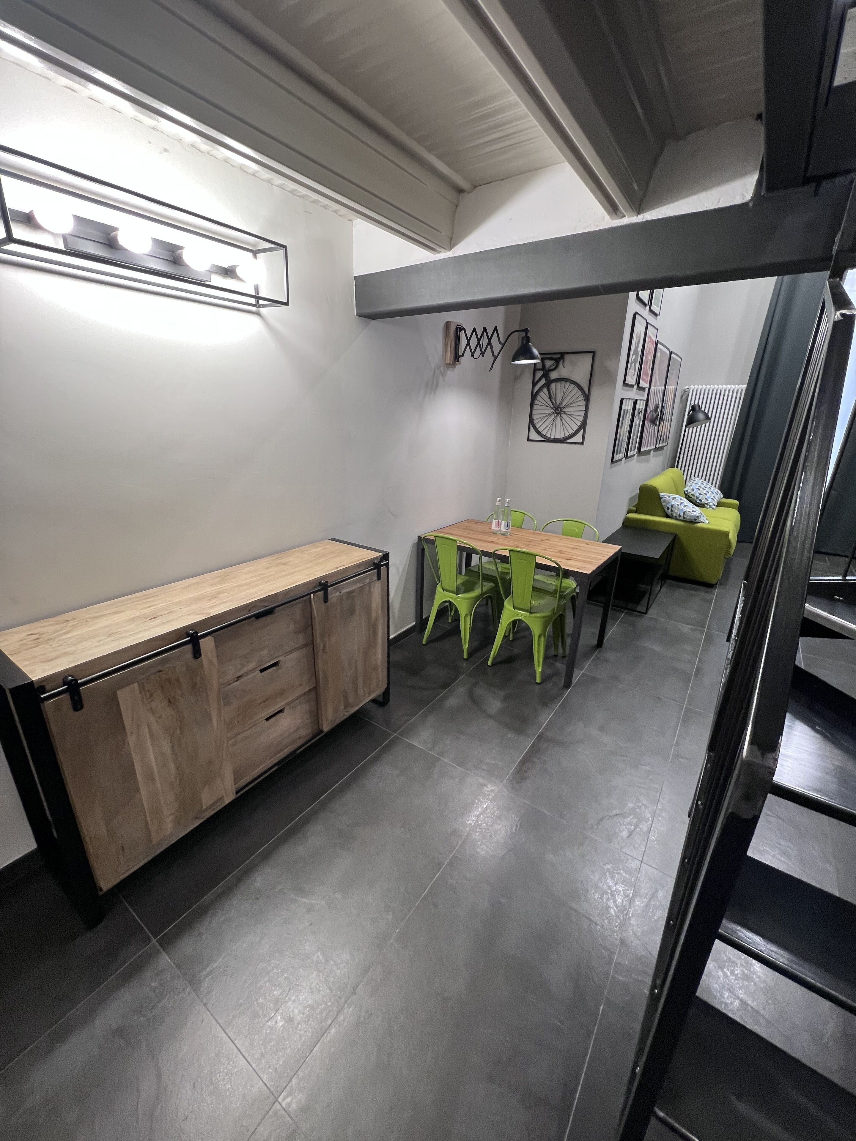 A modern kitchen with a wooden countertop, green chairs, and a dining table.
