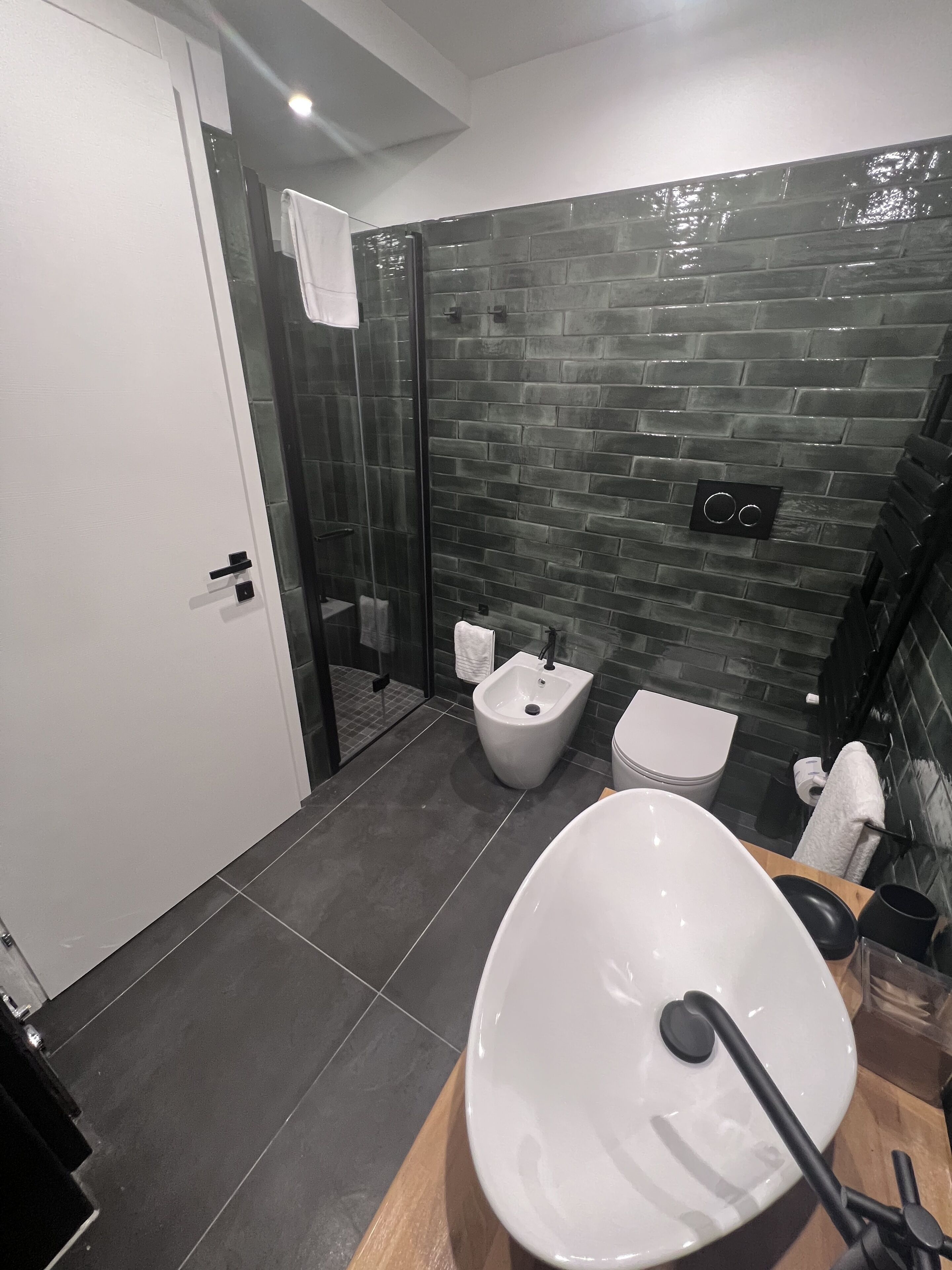 A modern bathroom with a large white sink, a bidet, and a toilet.