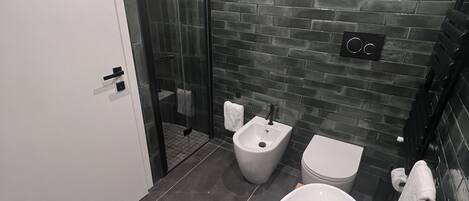 A modern bathroom with a large white sink, a bidet, and a toilet.