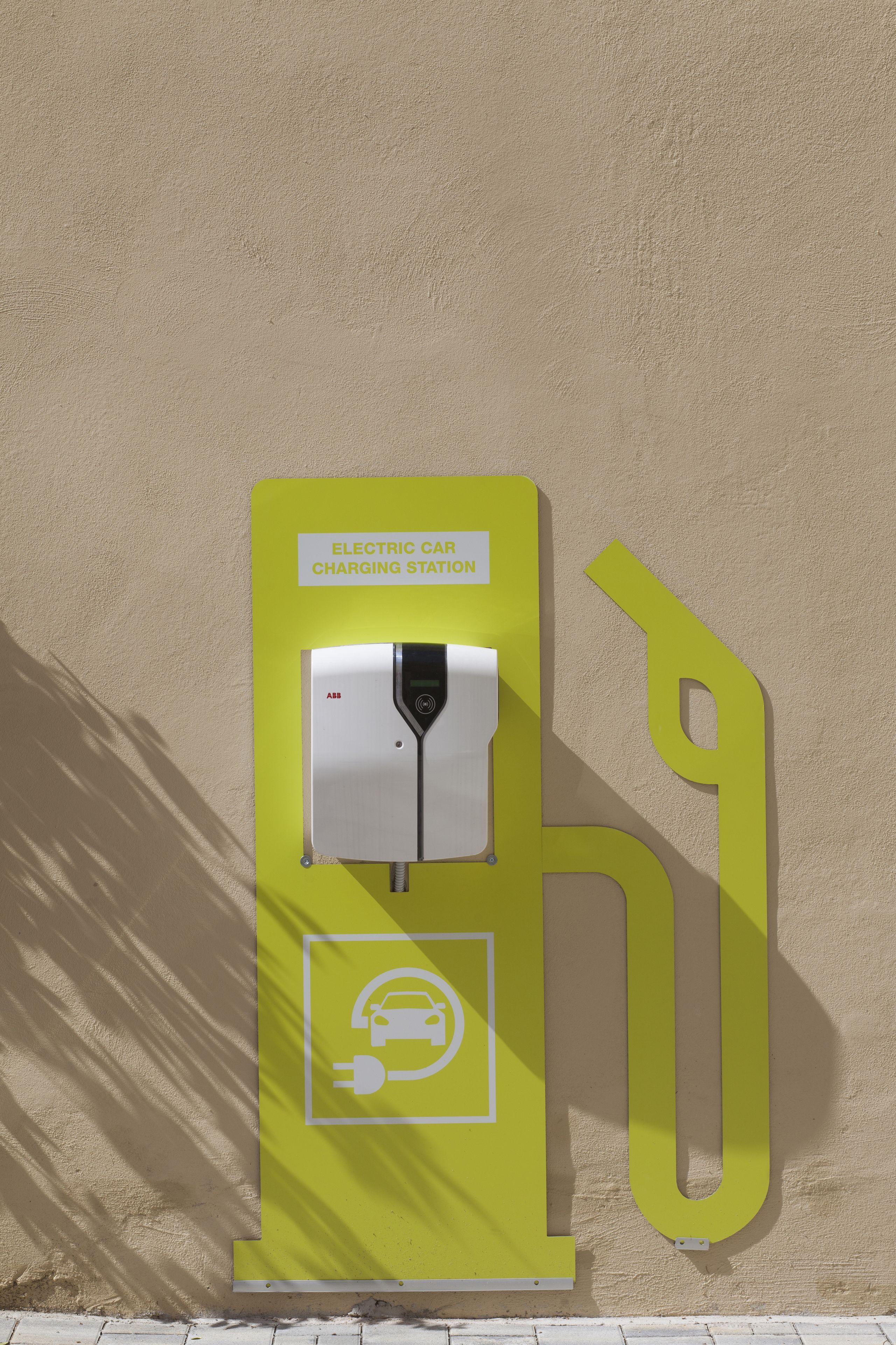 Una estación de carga para coche eléctrico amarillo, con un letrero que indica que es de la marca ABB.