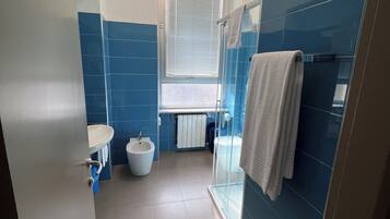 Ein modernes Badezimmer mit integriertem Bidet, Toilette und Duschkabine aus Glas.