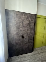 Un armadio capiente con due maniglie, una porta verde e un pavimento grigio.