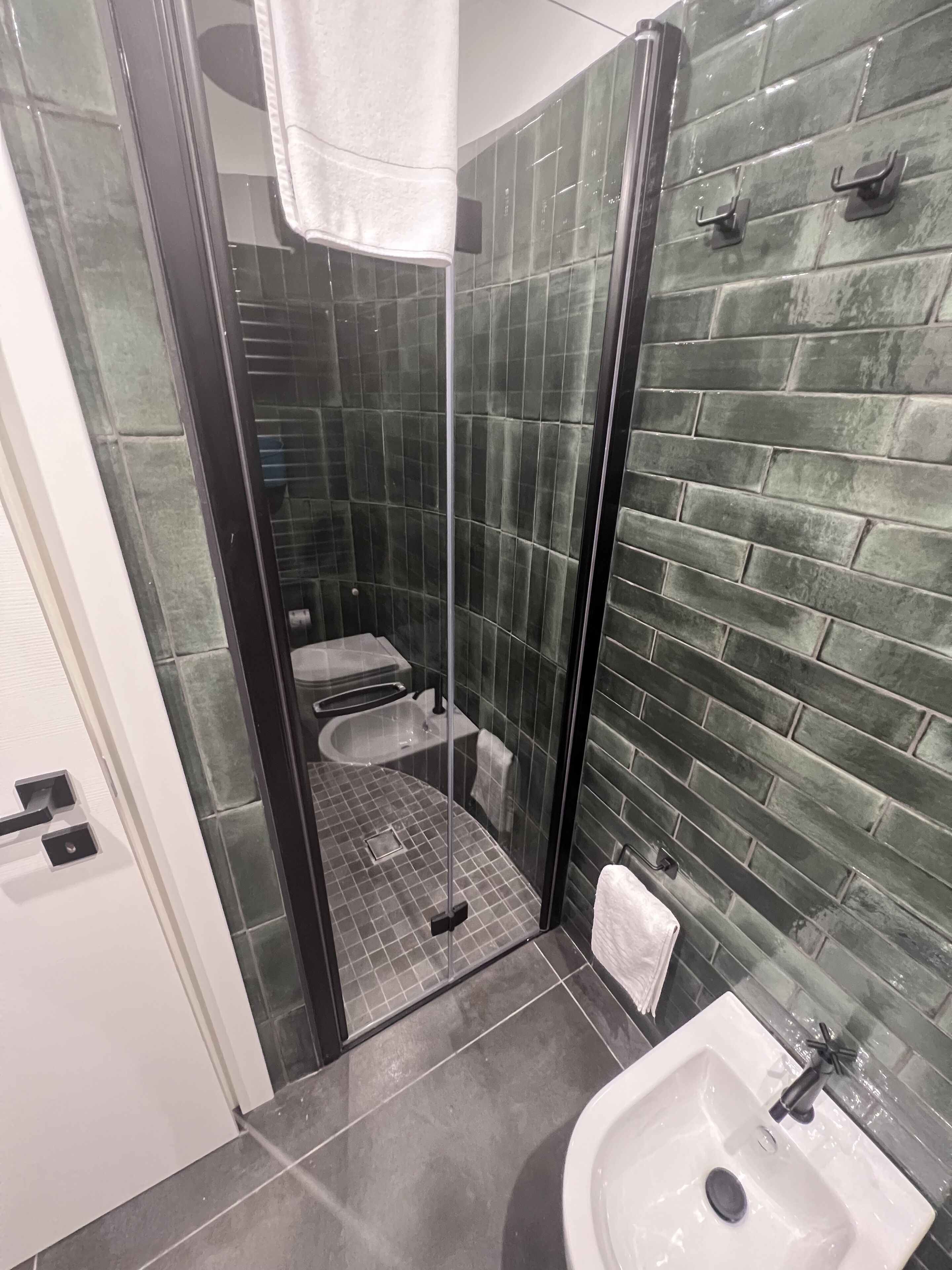 A bathroom with a glass-enclosed shower, a white sink, and a tiled floor.