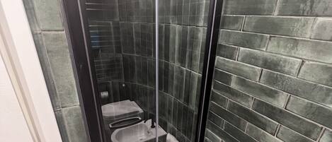 A bathroom with a glass-enclosed shower, a white sink, and a tiled floor.