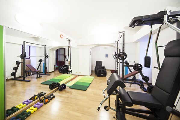 A gym with various exercise equipment, a green mat, and dumbbells. - Residence Star (Turin)