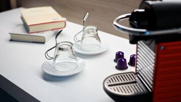 Eine Kaffeemaschine mit rotem Fuß und einer Glas-Kaffeekanne auf einem weißen Tisch.