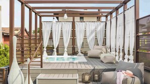 A rooftop terrace with a pool, seating area, and pergola with curtains. - Enjoy Garda Hotel (Peschiera del Garda)