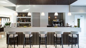 A modern bar area with a central island, bar stools, and pendant lighting. - Enjoy Garda Hotel (Peschiera del Garda)