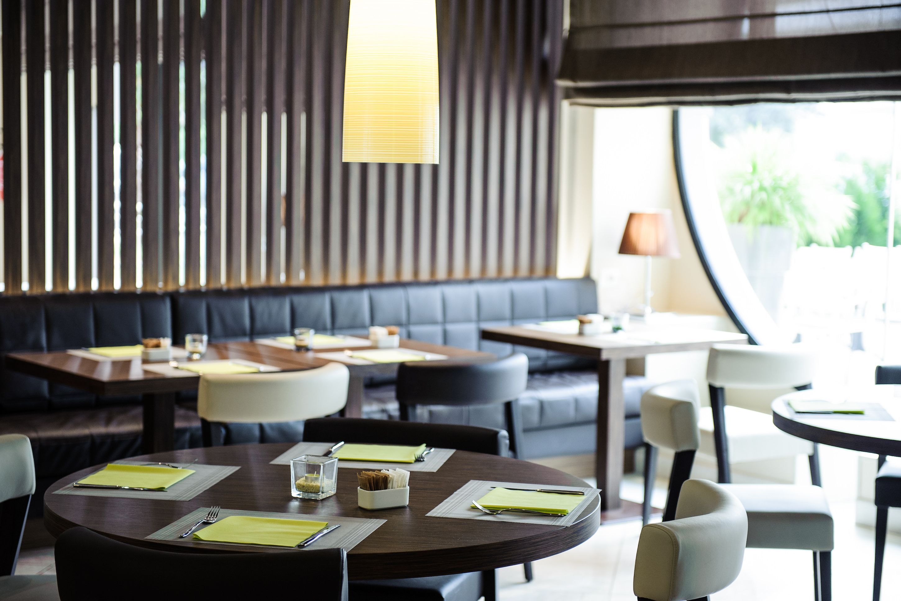 A restaurant with round tables, black leather booths, and a modern interior design.
