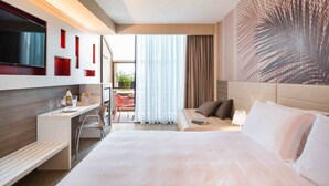 A modern hotel room with a large bed, a desk with a chair, a TV, and a view of the outdoors. - Enjoy Garda Hotel (Peschiera del Garda)