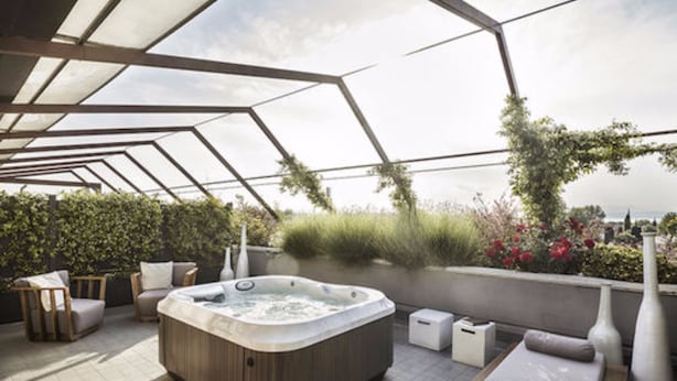 A rooftop terrace with a hot tub, seating area, and a view of the city. - Enjoy Garda Hotel (Peschiera del Garda)