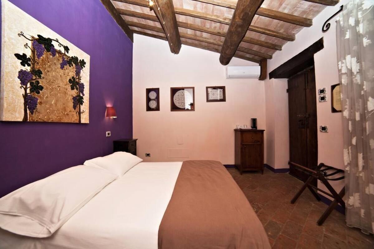 Une chambre à coucher comprenant un lit, une œuvre d’art accrochée au mur, un plafond en bois, une porte et un petit meuble.